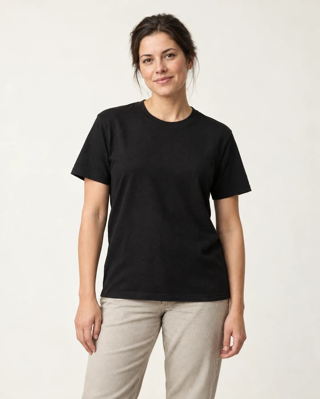 Woman wearing a black crew-neck tee against a plain off-white studio background.